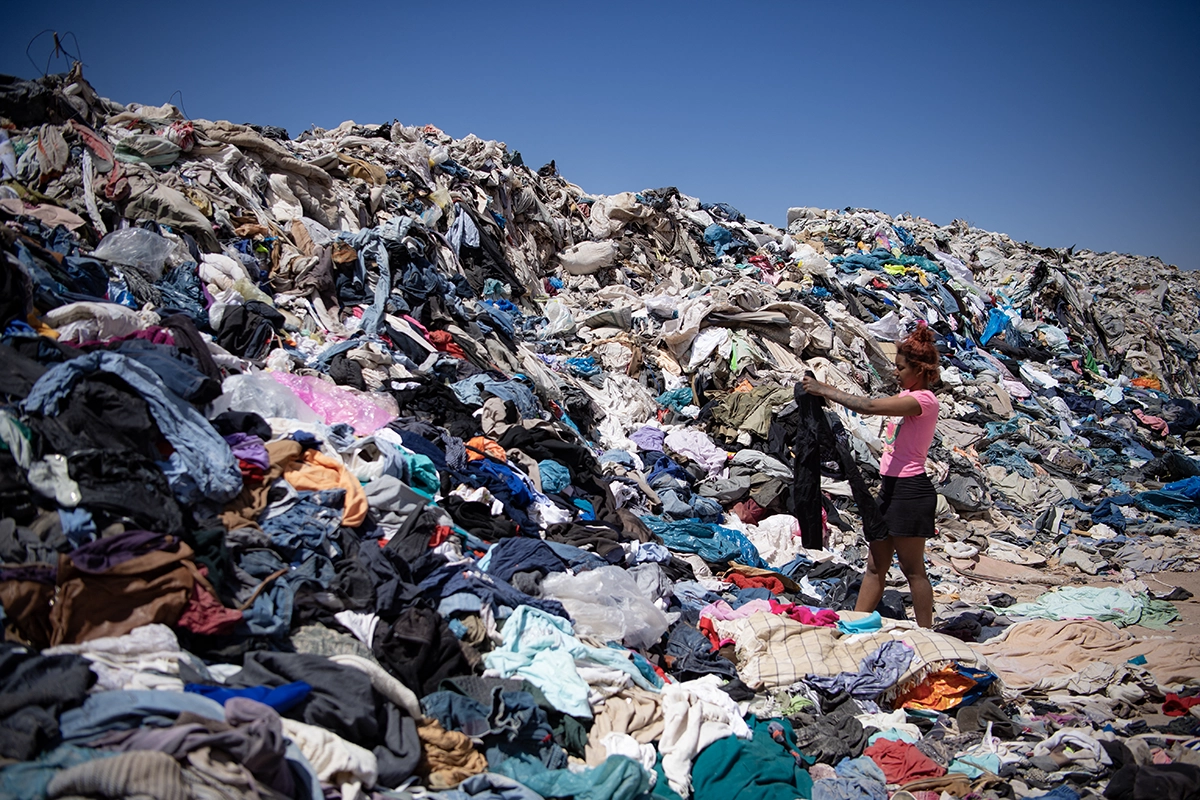 En kvinde gennemgår en enorm bunke af kasseret tøj i Atacama-ørkenen i Chile, hvor store mængder fast fashion-affald dumpes hvert år.